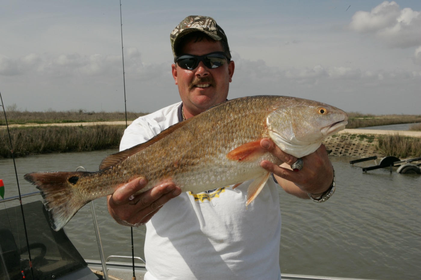 Redfish (Sciaenops ocellatus) held by an angler, showing copper body and tail spot